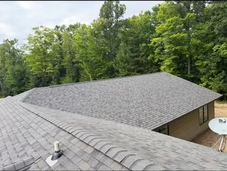 Roofline with new shingles and the woods behind